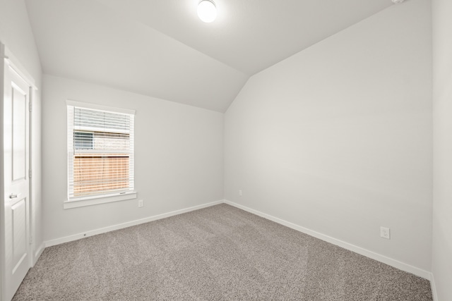 spare room with carpet and vaulted ceiling