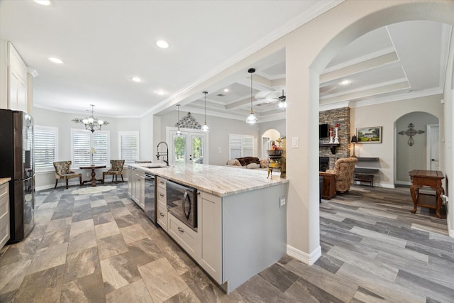 kitchen featuring white cabinets, decorative light fixtures, black microwave, refrigerator, and light stone counters