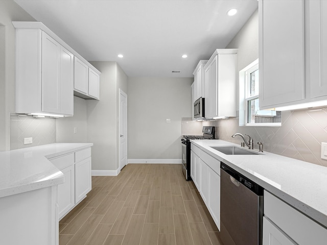 kitchen featuring light stone countertops, white cabinetry, sink, stainless steel appliances, and tasteful backsplash