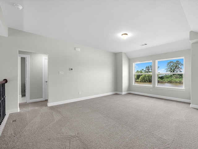 unfurnished living room featuring light carpet and vaulted ceiling