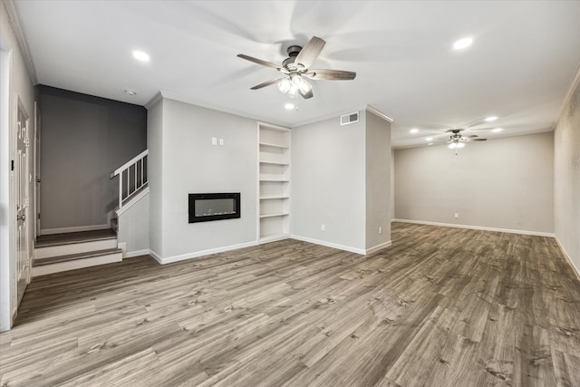 unfurnished living room with light wood-type flooring, ceiling fan, built in features, and crown molding