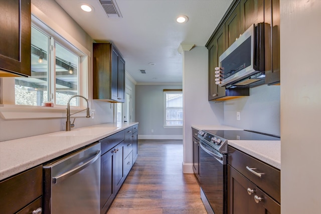 kitchen featuring wood-type flooring, sink, stainless steel appliances, and ornamental molding