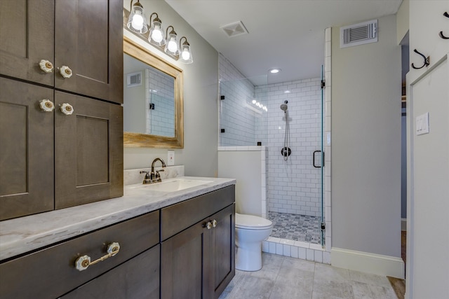 bathroom featuring tile patterned flooring, vanity, toilet, and a shower with shower door