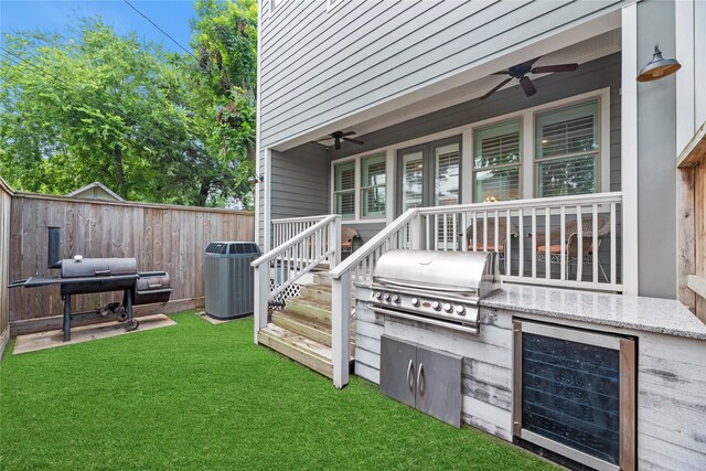 wooden deck with a yard, a grill, beverage cooler, and ceiling fan