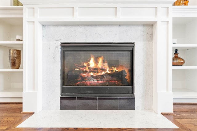 details with built in shelves, hardwood / wood-style floors, and a high end fireplace