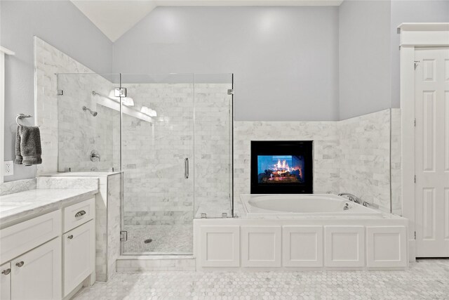 bathroom featuring independent shower and bath, vanity, and vaulted ceiling