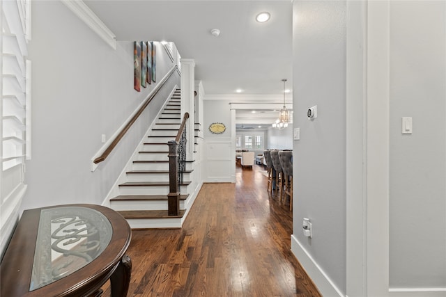 foyer featuring a notable chandelier, crown molding, and dark hardwood / wood-style flooring