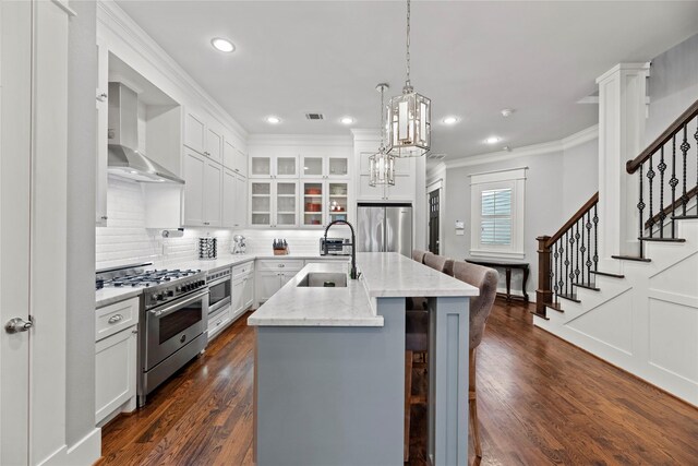 kitchen with an island with sink, stainless steel appliances, white cabinets, sink, and dark hardwood / wood-style flooring