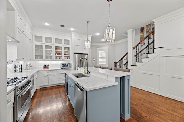 kitchen featuring an island with sink, stainless steel appliances, white cabinets, dark wood-type flooring, and sink