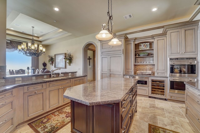 kitchen with wine cooler, sink, decorative light fixtures, double oven, and a center island