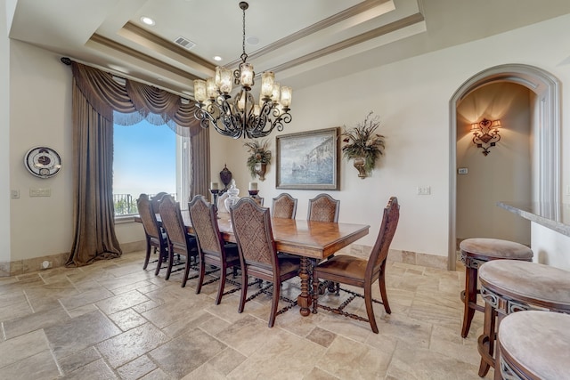 dining space with crown molding, a tray ceiling, and a chandelier