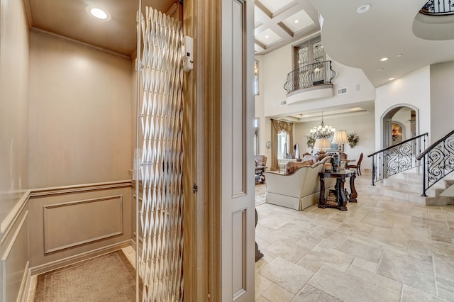 interior space with crown molding, coffered ceiling, and a notable chandelier