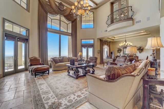 living room with a towering ceiling, a chandelier, and french doors