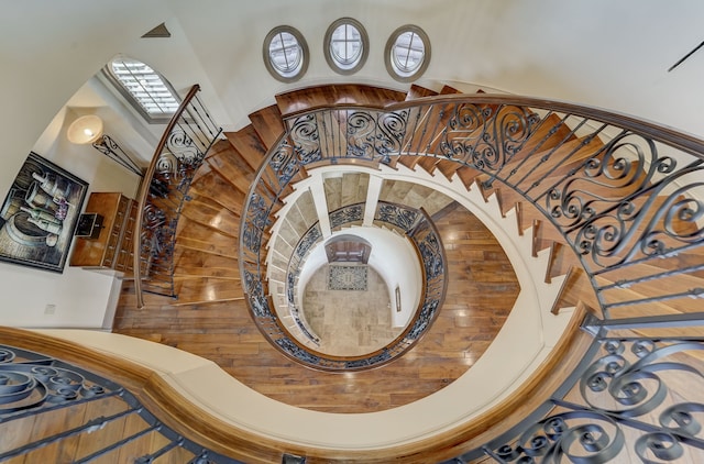 stairs featuring wood-type flooring, a high ceiling, and wooden walls