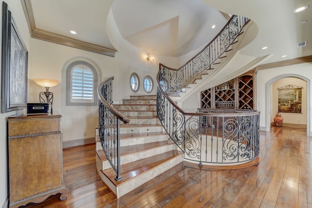 stairs with ornamental molding and hardwood / wood-style floors