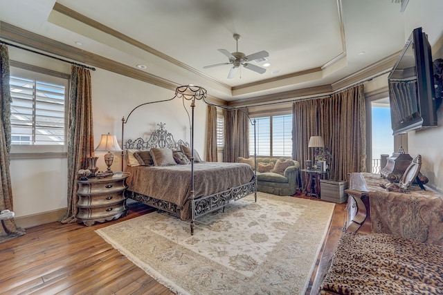 bedroom featuring ceiling fan, a tray ceiling, crown molding, and light hardwood / wood-style floors