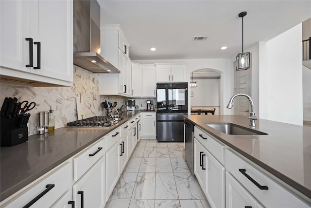 kitchen featuring stainless steel appliances, wall chimney range hood, white cabinets, and sink