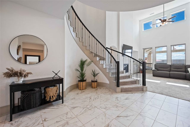 carpeted entrance foyer featuring ceiling fan and a high ceiling