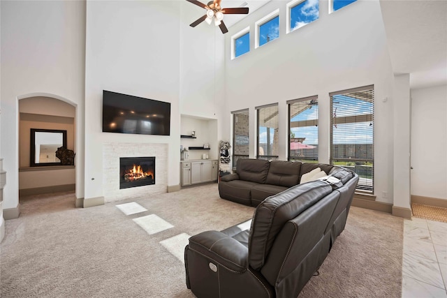 carpeted living room featuring a high ceiling, ceiling fan, and built in features