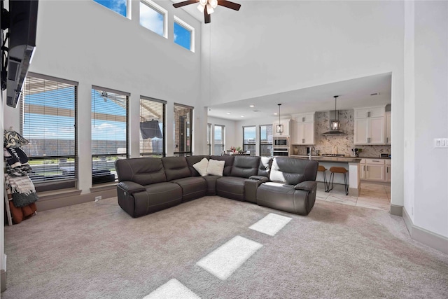 carpeted living room featuring ceiling fan, sink, and a high ceiling