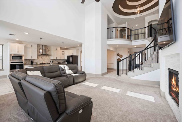 living room featuring light tile patterned floors, a stone fireplace, an inviting chandelier, and a high ceiling