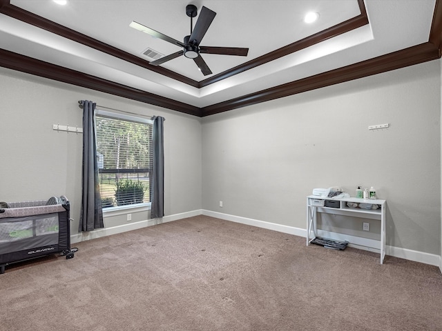 carpeted empty room featuring ceiling fan, a raised ceiling, and crown molding