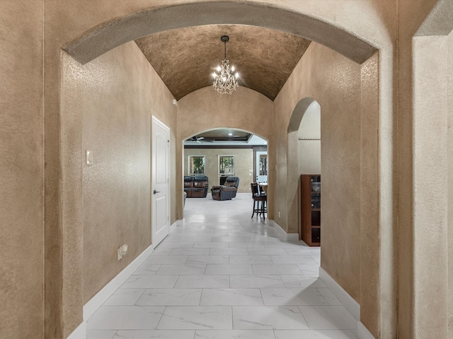 hallway with lofted ceiling and a chandelier