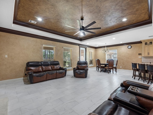 living room with a textured ceiling, ceiling fan with notable chandelier, crown molding, and a raised ceiling