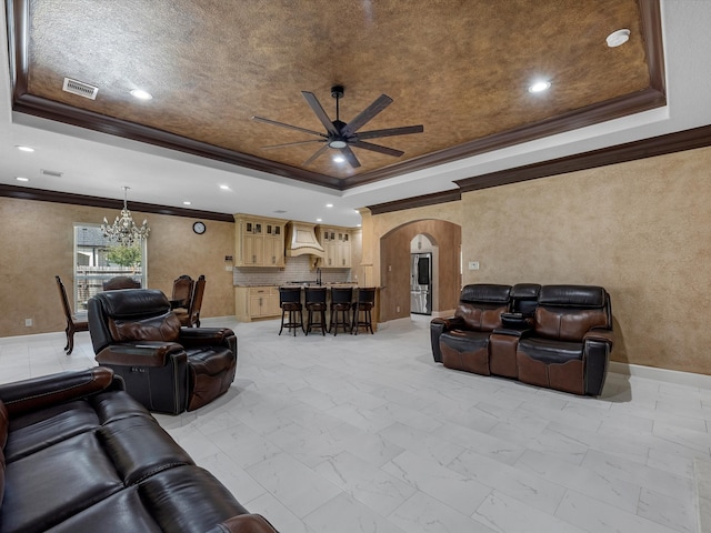 living room featuring a textured ceiling, ceiling fan with notable chandelier, ornamental molding, and a tray ceiling