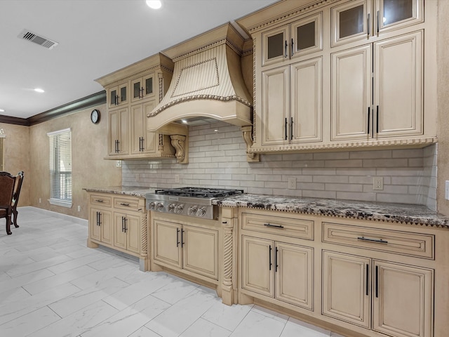 kitchen with custom exhaust hood, ornamental molding, stainless steel gas stovetop, dark stone counters, and decorative backsplash