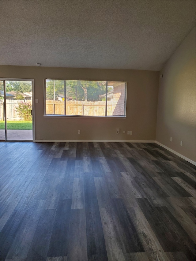 spare room featuring a textured ceiling and dark hardwood / wood-style floors