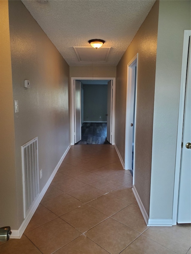 hallway featuring a textured ceiling and light tile patterned floors