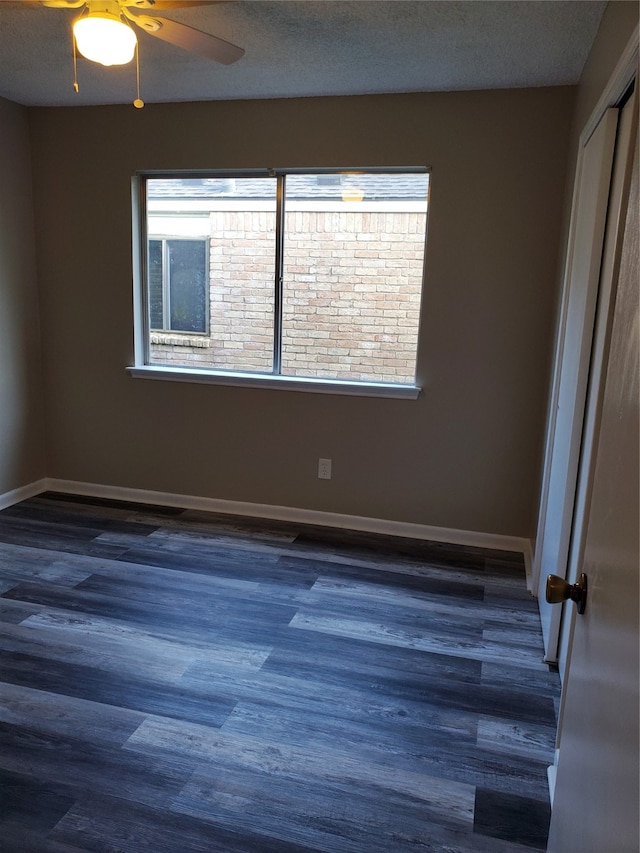 spare room with ceiling fan, dark wood-type flooring, and a textured ceiling