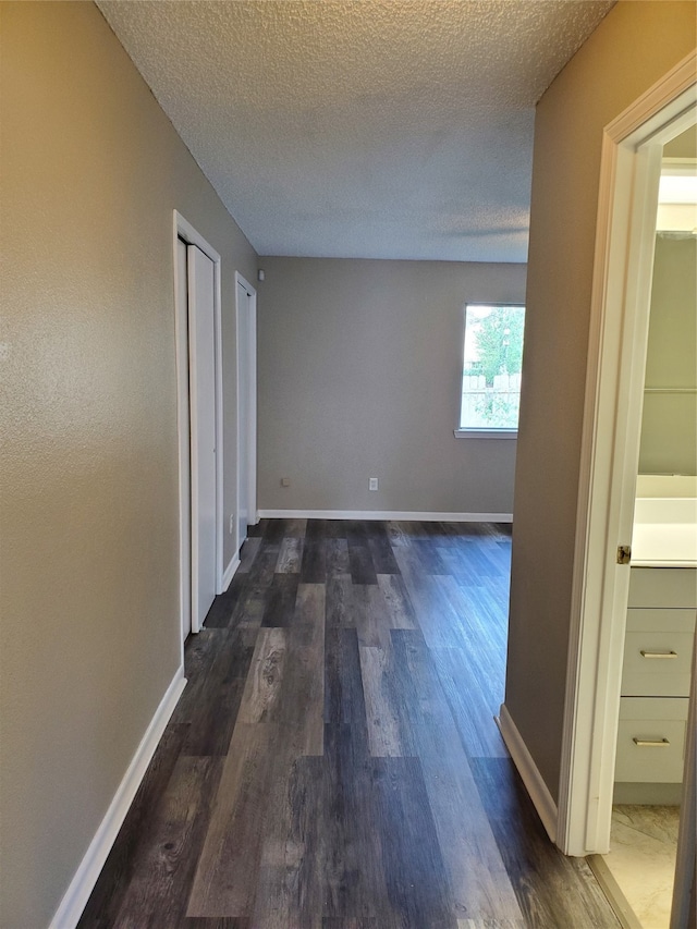 hall with a textured ceiling and dark hardwood / wood-style floors