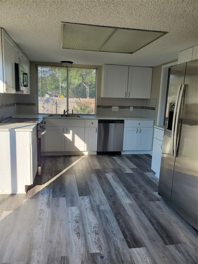 kitchen with appliances with stainless steel finishes, decorative backsplash, white cabinetry, and dark hardwood / wood-style floors