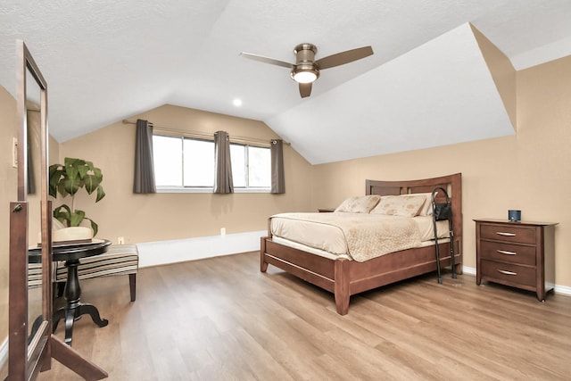 bedroom featuring a textured ceiling, light hardwood / wood-style floors, lofted ceiling, and ceiling fan