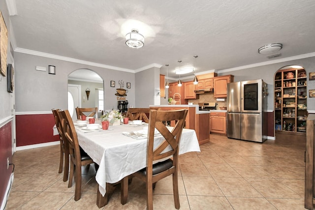 dining area with a textured ceiling, light tile patterned flooring, and ornamental molding