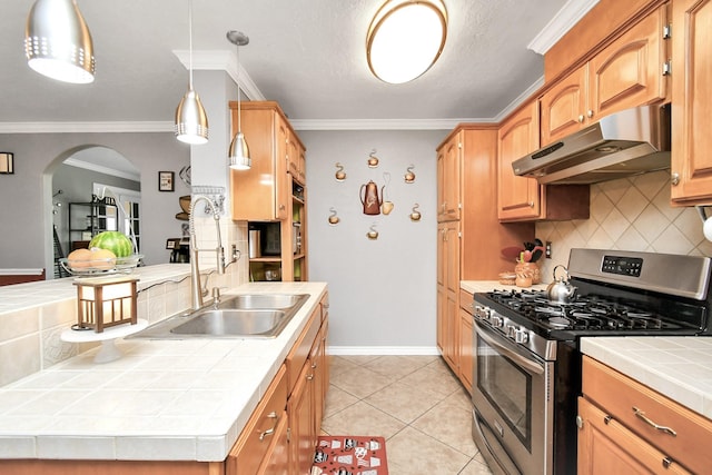 kitchen featuring light tile patterned flooring, stainless steel gas range oven, backsplash, tile countertops, and decorative light fixtures