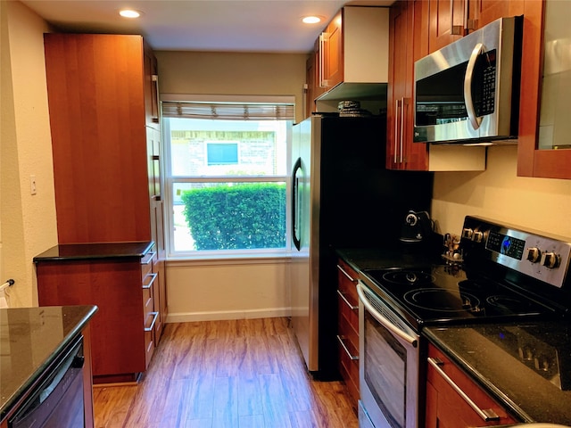 kitchen featuring appliances with stainless steel finishes, light wood-type flooring, and dark stone counters