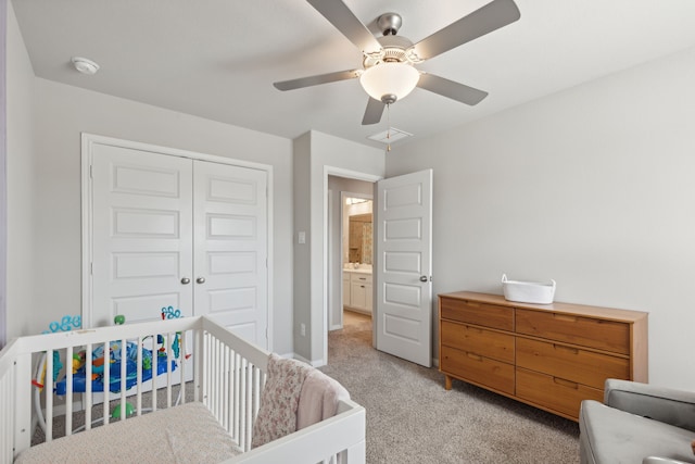 carpeted bedroom with a crib, a closet, and ceiling fan