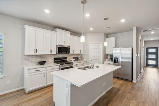 kitchen featuring stainless steel appliances, white cabinetry, hanging light fixtures, and sink