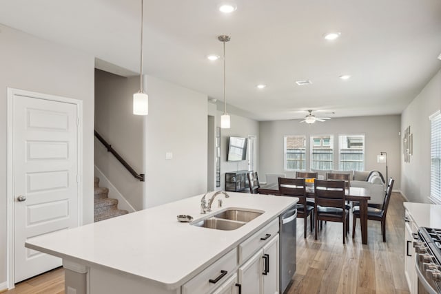 kitchen featuring sink, hanging light fixtures, light hardwood / wood-style flooring, a center island with sink, and appliances with stainless steel finishes