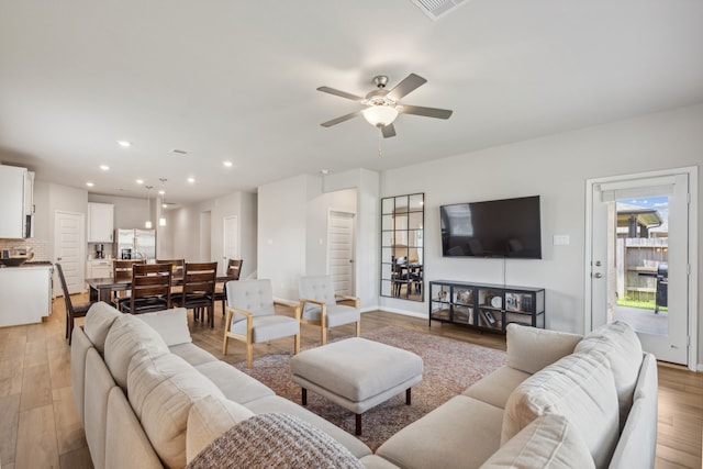 living room featuring ceiling fan and light hardwood / wood-style floors