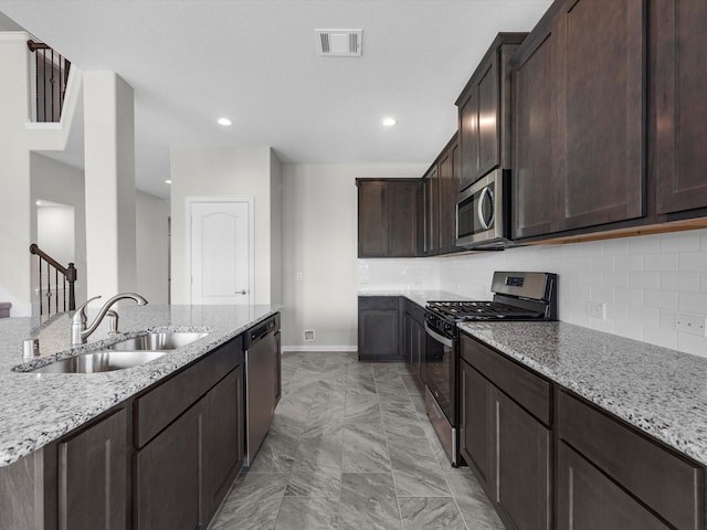 kitchen featuring dark brown cabinets, light stone countertops, stainless steel appliances, and sink