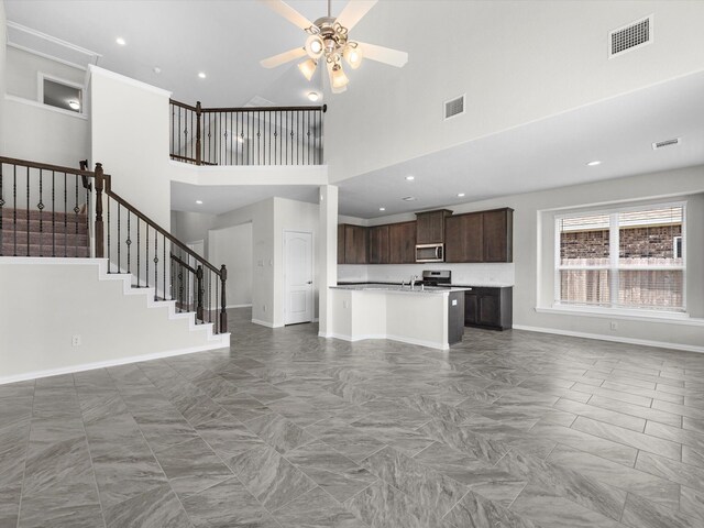 unfurnished living room featuring a towering ceiling and ceiling fan