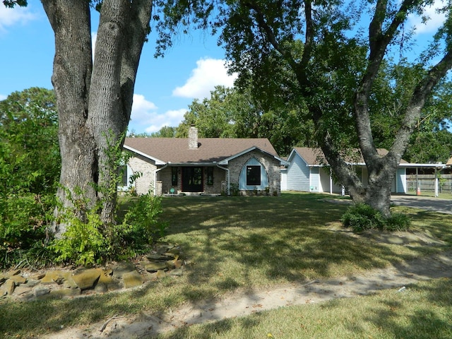 ranch-style home with a chimney, a front lawn, a carport, and brick siding