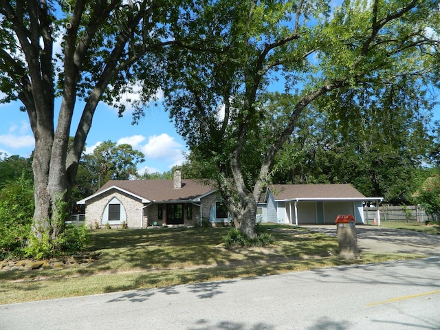 ranch-style home featuring driveway, a chimney, fence, a carport, and a front yard