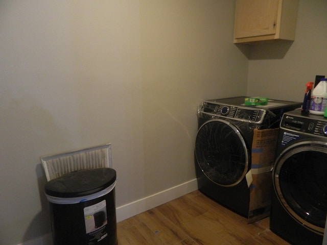 laundry area with washing machine and dryer, baseboards, cabinet space, and light wood finished floors