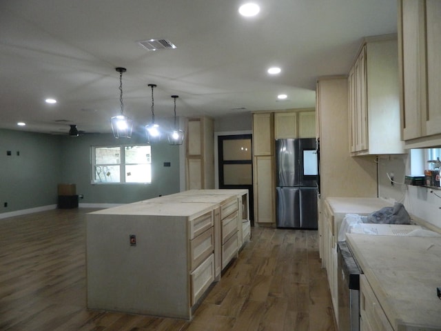 kitchen with recessed lighting, visible vents, freestanding refrigerator, a kitchen island, and wood finished floors