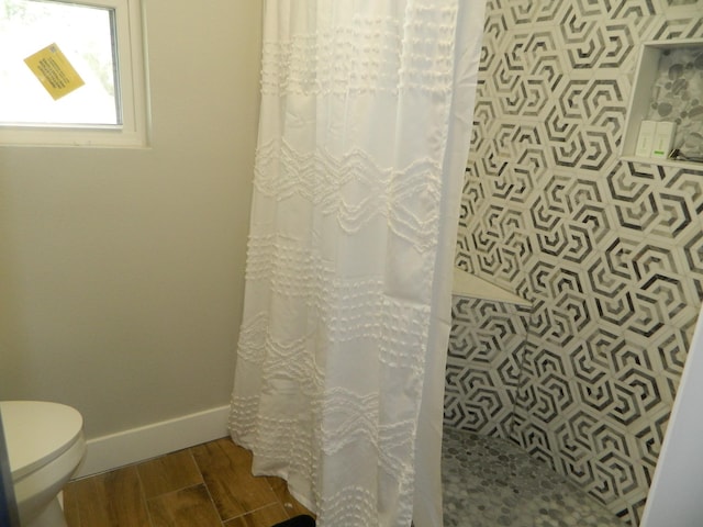 full bath featuring toilet, a shower with curtain, baseboards, and wood finished floors